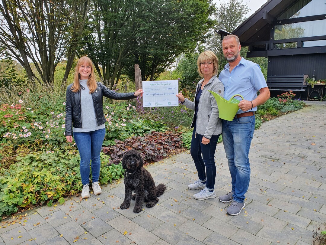 Katharina Peters (l., VGL NRW) besuchte die Gewinner Iris und Egon Hoffmann zur Scheckbergabe in ihrem Vorgarten in Emmerich.